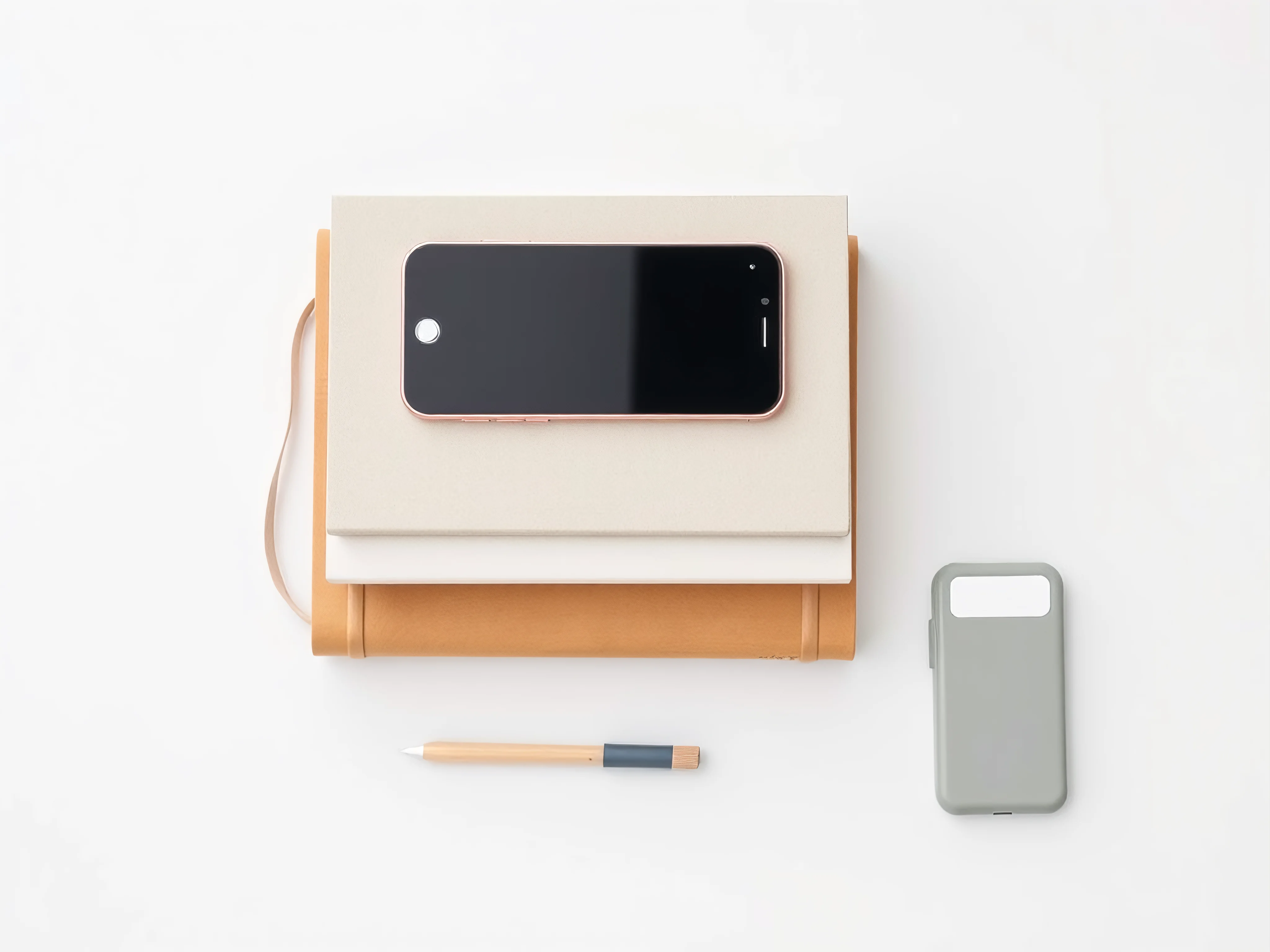 Simple living tools, minimalist books, smartphone, label maker in a flat lay.